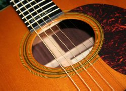 Front detail of CF Martin's very popular 000-28EC model, showing the solid Sitka spruce soundboard, finely inlaid herringbone 
              rosette and their instantly recognisable, much-copied, trademark "comma-shaped" pickguard